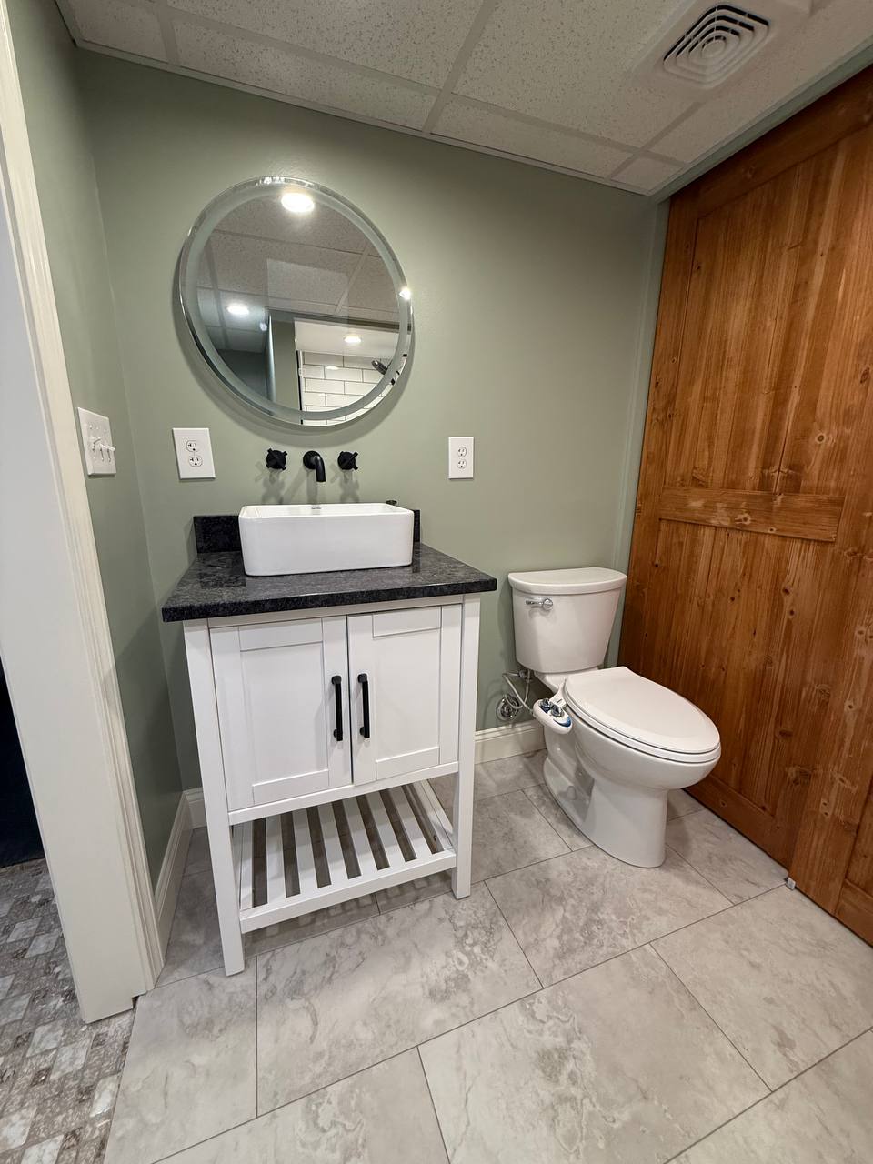 Vessel sink on a vanity with round mirror and toilet in a bathroom