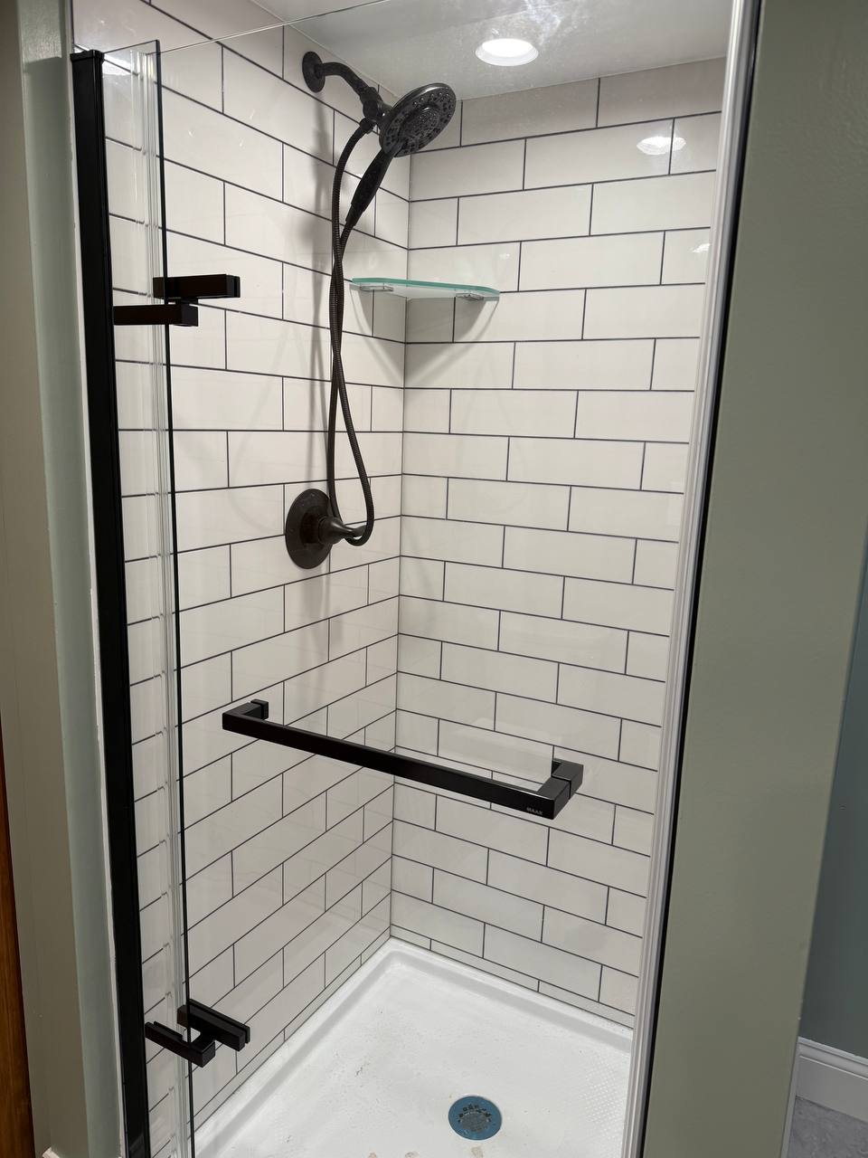 Walk-in shower with white subway tile, matte black fixtures and grab bar