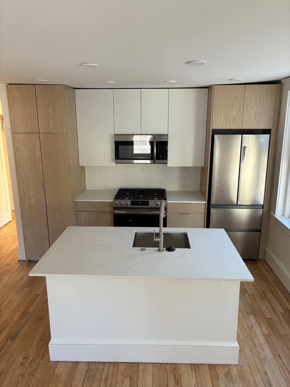 Kitchen with quartz island sink, gas range and stainless refrigerator