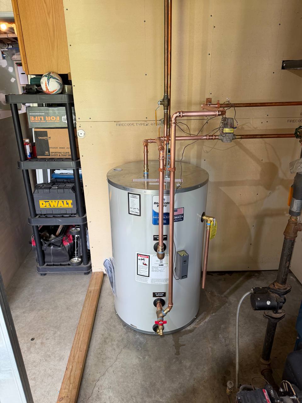 Indirect water heater with copper supply piping and a shut-off valve in a utility area