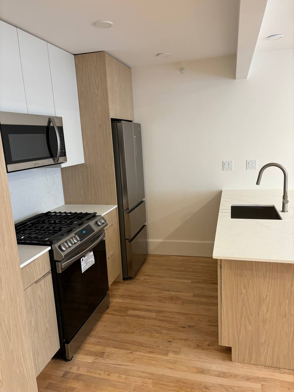 Kitchen with stainless gas range, over-range microwave and quartz countertop sink