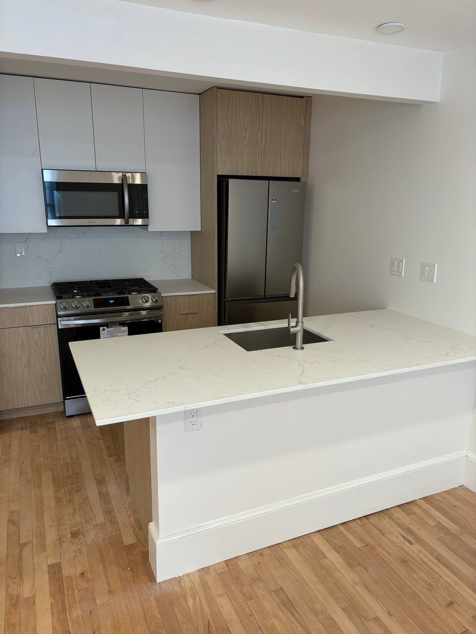 Kitchen with quartz peninsula, single-basin sink, gas range and stainless refrigerator