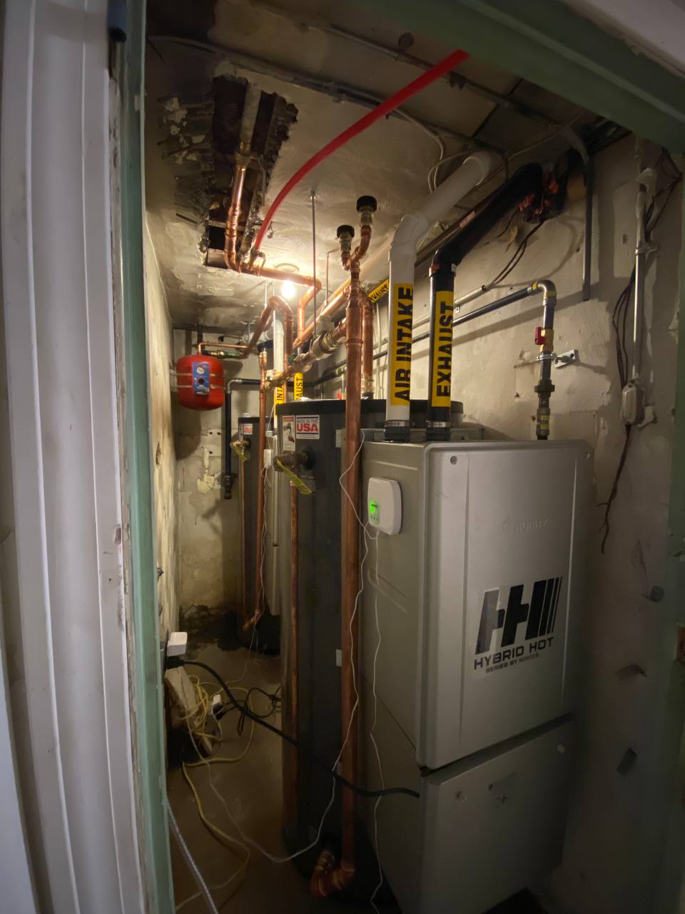 Tankless water heater with copper piping, air intake and exhaust vents in basement