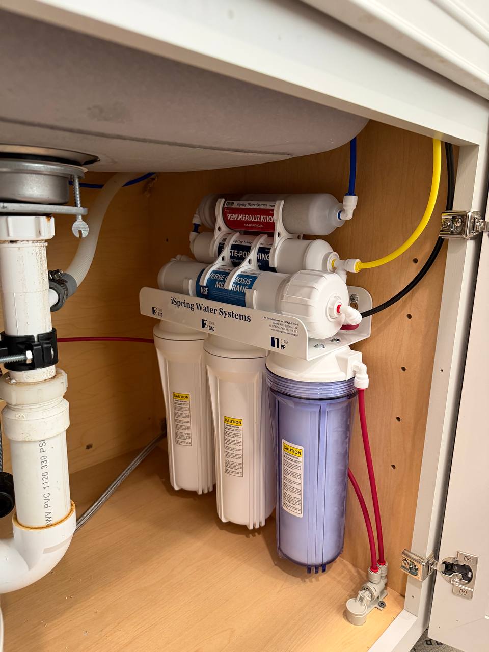 Under-sink reverse osmosis water filtration system with filter housings and PVC drain
