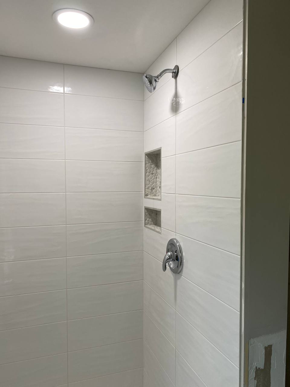 Tiled shower stall with chrome showerhead, control valve and recessed niches