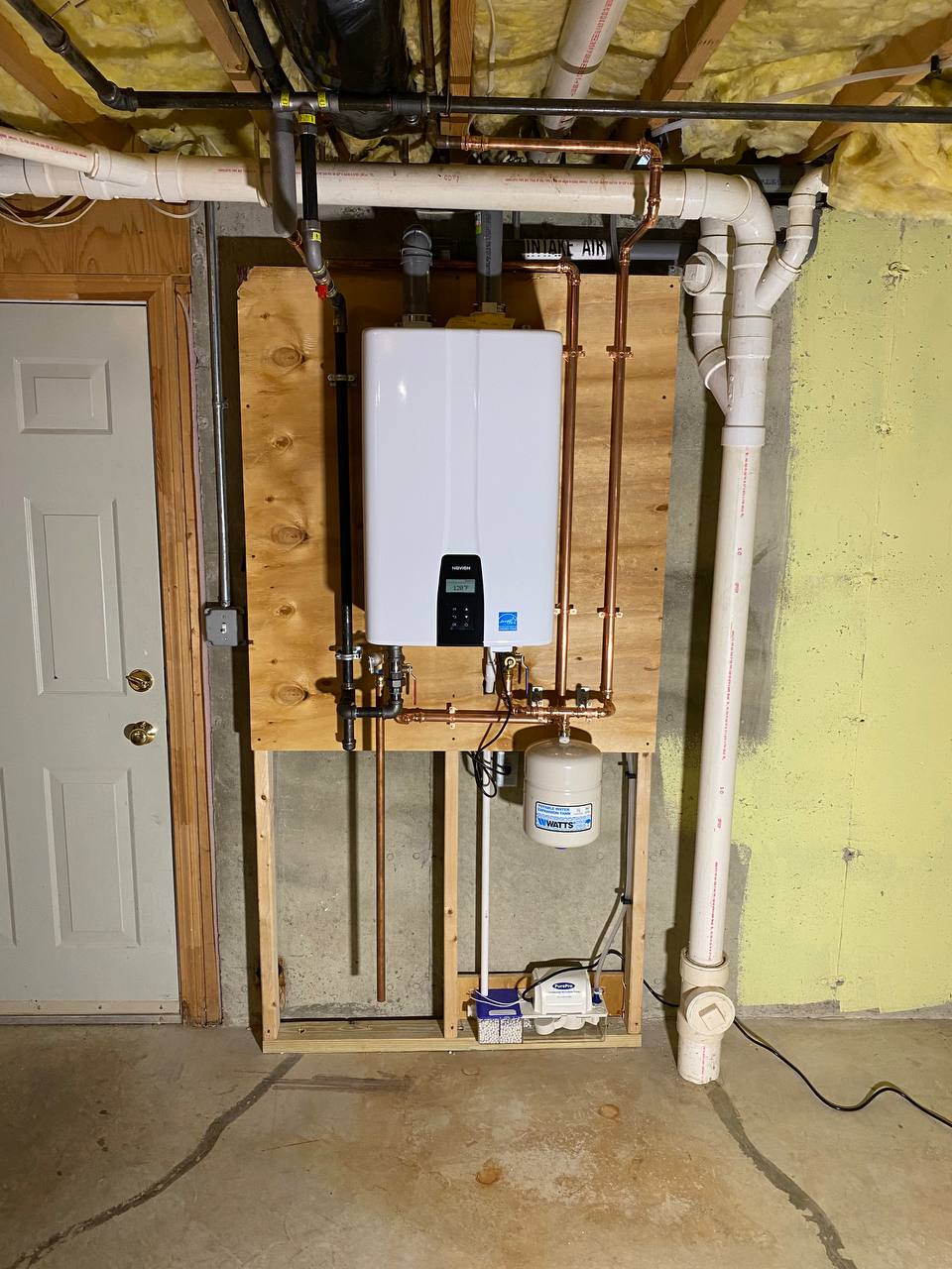 Wall-mounted tankless water heater with copper piping, PVC venting and expansion tank