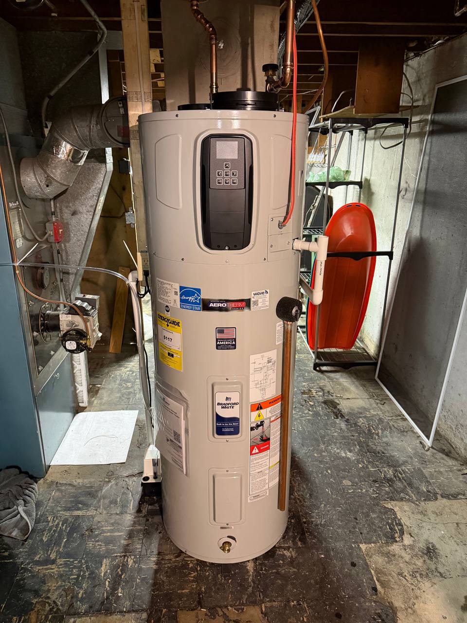 Hybrid heat pump water heater with digital control panel and copper lines in a basement
